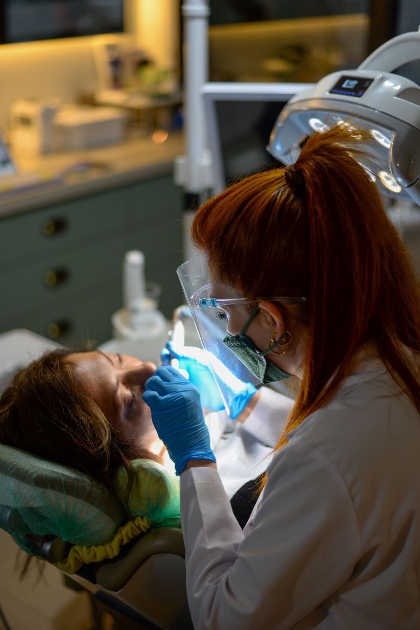 Clinician polymerizing an adhesive restoration with a blue LED curing light